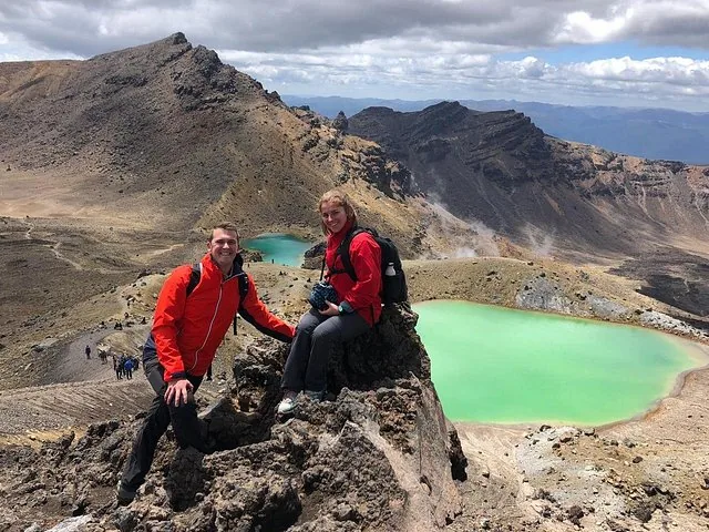 Deux randonneurs assis sur des rochers surplombant les Lacs Émeraude d'un vert éclatant.