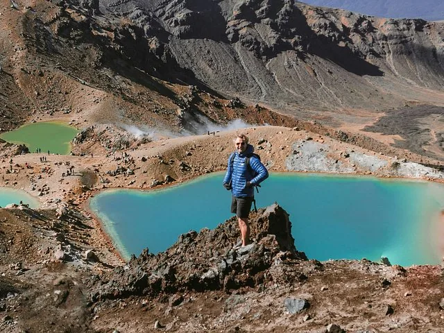 Senderista de pie sobre los Lagos Esmeralda, de un azul impactante, en un cráter volcánico.